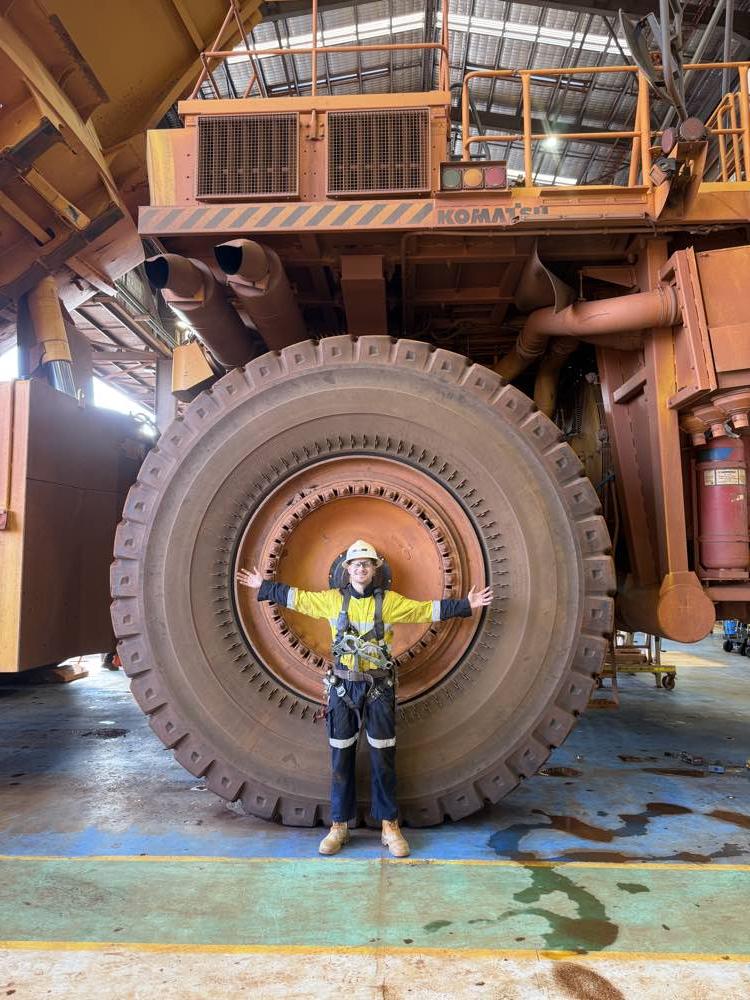 A worker next to the wheel of a mining haul truck