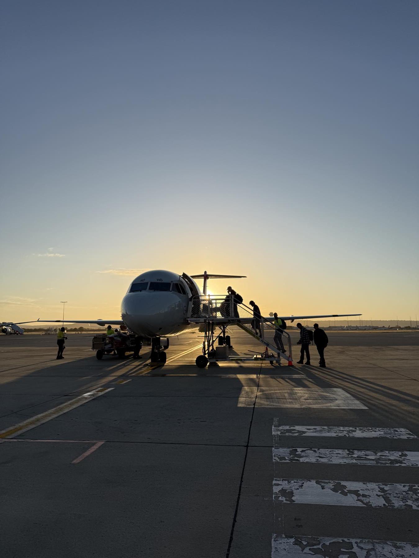 A FIFO charter plane on the tarmac at sunrise as workers walk up the stairs for their roster